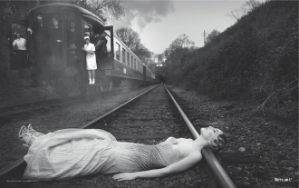 Black and white photograph of a woman in a white dress lying on train tracks, for The Joy of Catharsis by Malin James